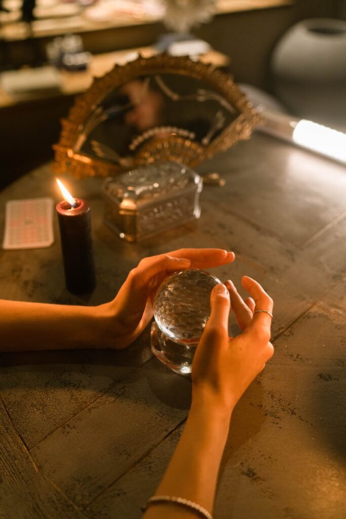 Hands hold a crystal ball in a candlelit mystical setting ideal for fortune-telling themes.