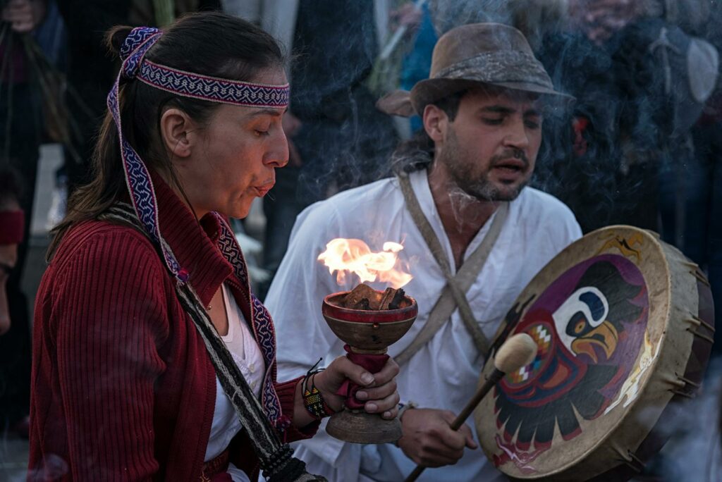 Cultural ritual with fire and music in Bogotá, Colombia, showcasing traditional attire and instruments.