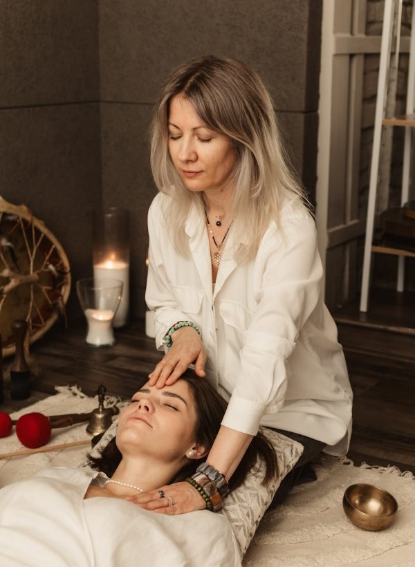 Therapist gently touching woman's forehead during session